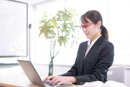 コーディング中の女性エンジニア社員がノートパソコンでプログラミング作業