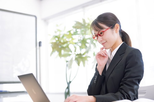 オフィスでパソコン画面を集中して見つめる女性