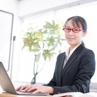 笑顔で接客対応をする黒いスーツの女性社員の写真
