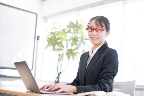 笑顔で接客対応をする黒いスーツの女性社員