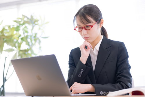 真剣に数字を追う経理の女性、パソコンでデスクワーク