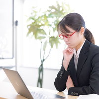 パソコンを見つめて真剣に悩む女性講師の顔の写真