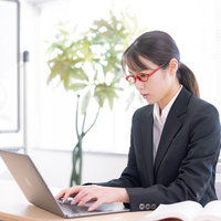 黒いスーツで真剣にキーボードをたたく女性講師の写真