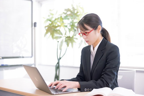 黒いスーツで真剣にキーボードをたたく女性講師