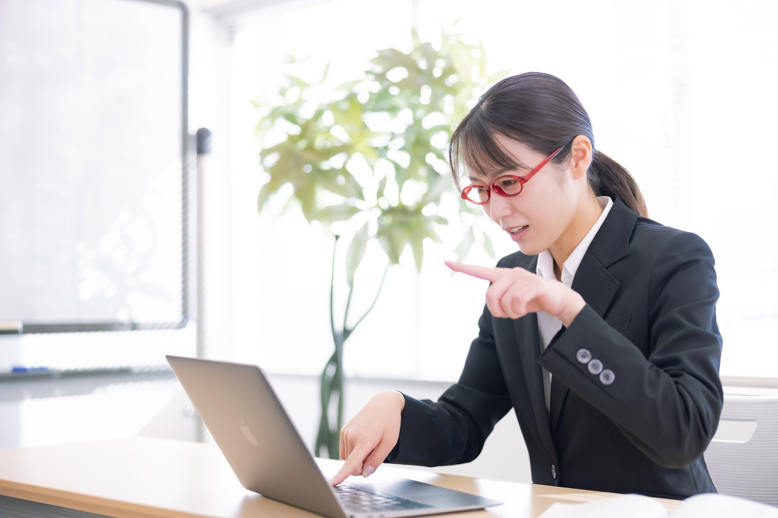パソコン教室で人差し指タイピングを真剣に学ぶスーツ姿の女性［モデル：SAKI］