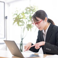 人差し指タイピングを矯正中の新人女性のデスクワークの写真