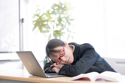 研修の合間にノートパソコンの前で居眠りする女性