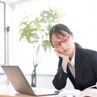 肘をついてパソコンで調べものする事務員の女性の写真