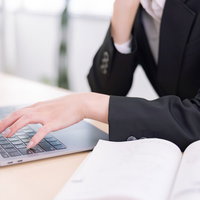 キーボードを叩く女性社員の指先とタイピング動作の写真
