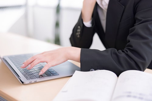 キーボードを叩く女性社員の指先とタイピング動作