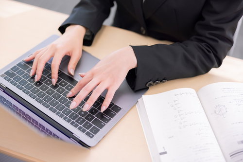 ノートパソコンでタイピングする女性の手元
