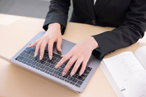 キーボードでタイピングする女性事務員の手元