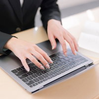 ノートパソコンのキーボードでタイピング中の女性の手元の写真