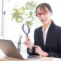 虫眼鏡で検閲チェックをするビジネスウーマンの写真