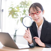 虫メガネでノートパソコンを検索する女子社員の写真