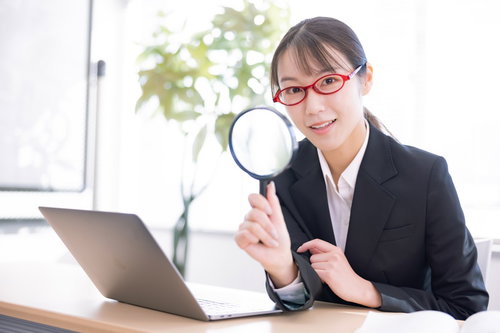 虫メガネでノートパソコンを検索する女子社員