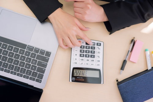 電卓で計算するデスクワーク中の女性の手元