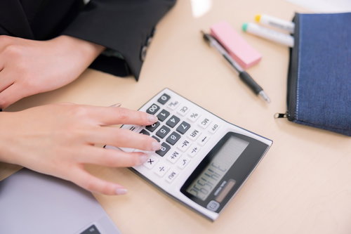 電卓のボタンを押す女性の手元