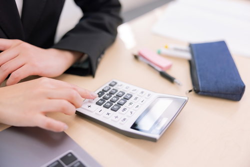 電卓を使う事務作業の手元、経理業務と計算業務