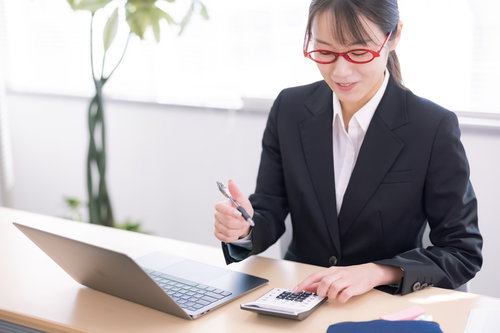 赤い眼鏡をかけた電卓を使う女性事務員の経理業務