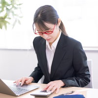 電卓とノートパソコンを使いこなす女性社員の写真