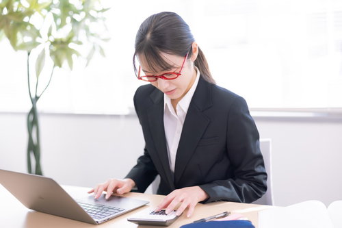 電卓とノートパソコンを使いこなす女性社員