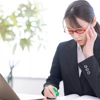 困り果てて修正テープを持つ女性の写真