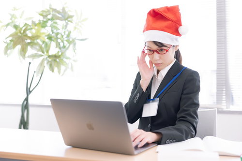 サンタ帽をかぶってパソコンに向かう女性会社員