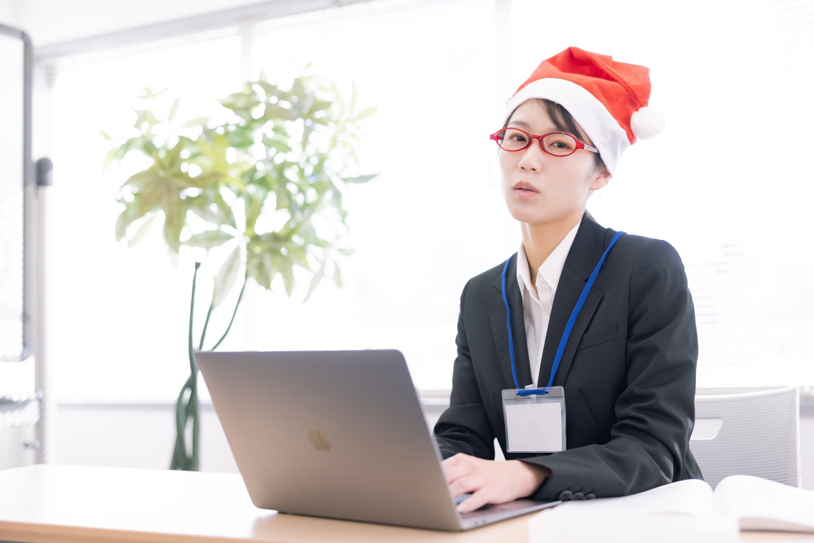 サンタ帽をかぶりオフィスでパソコン作業をする眼鏡をかけた女性［モデル：SAKI］