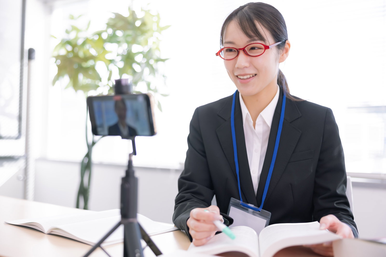 オンライン会議に参加する眼鏡をかけたスーツ姿の女性［モデル：SAKI］