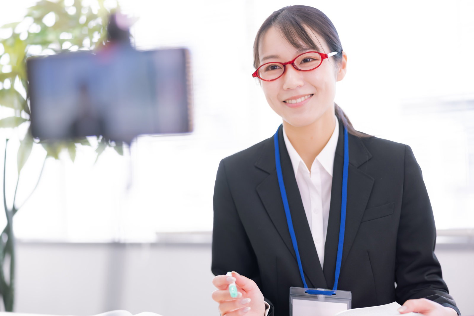 眼鏡をかけた女性講師が笑顔でオンライン講義をしている様子［モデル：SAKI］