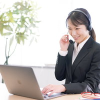 ヘッドセットを着用して笑顔でクレーム対応中の女性オペレーターの写真