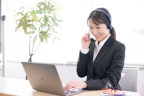 ヘッドセットを着用して笑顔でクレーム対応中の女性オペレーター