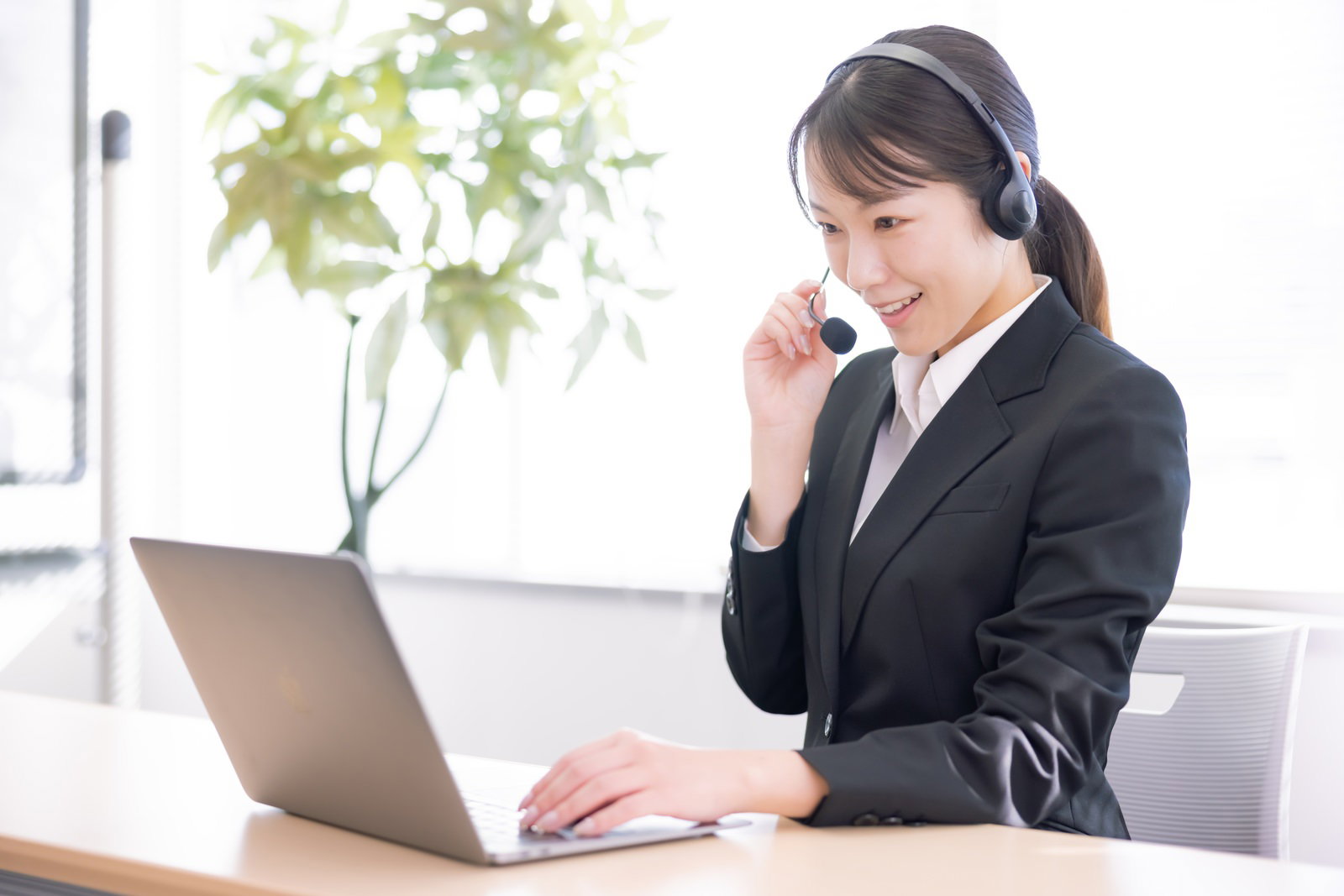 ヘッドセットで通話しながら作業する女性オペレーター［モデル：SAKI］