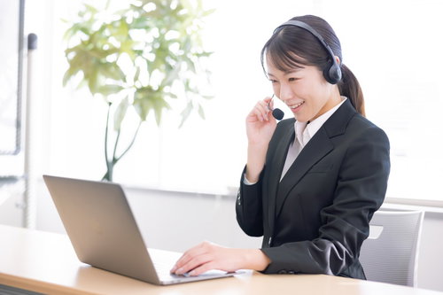 ヘッドセットを着けてコール業務をこなす笑顔の女性オペレーター