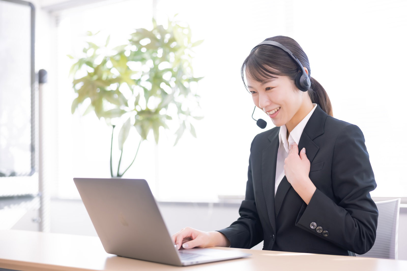 ヘッドセットを装着し笑顔で電話対応をする女性オペレーター［モデル：SAKI］