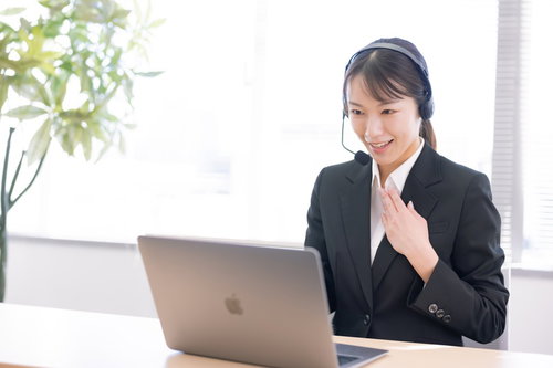 まごころ丁寧にテレアポする黒いスーツの女性オペレーター