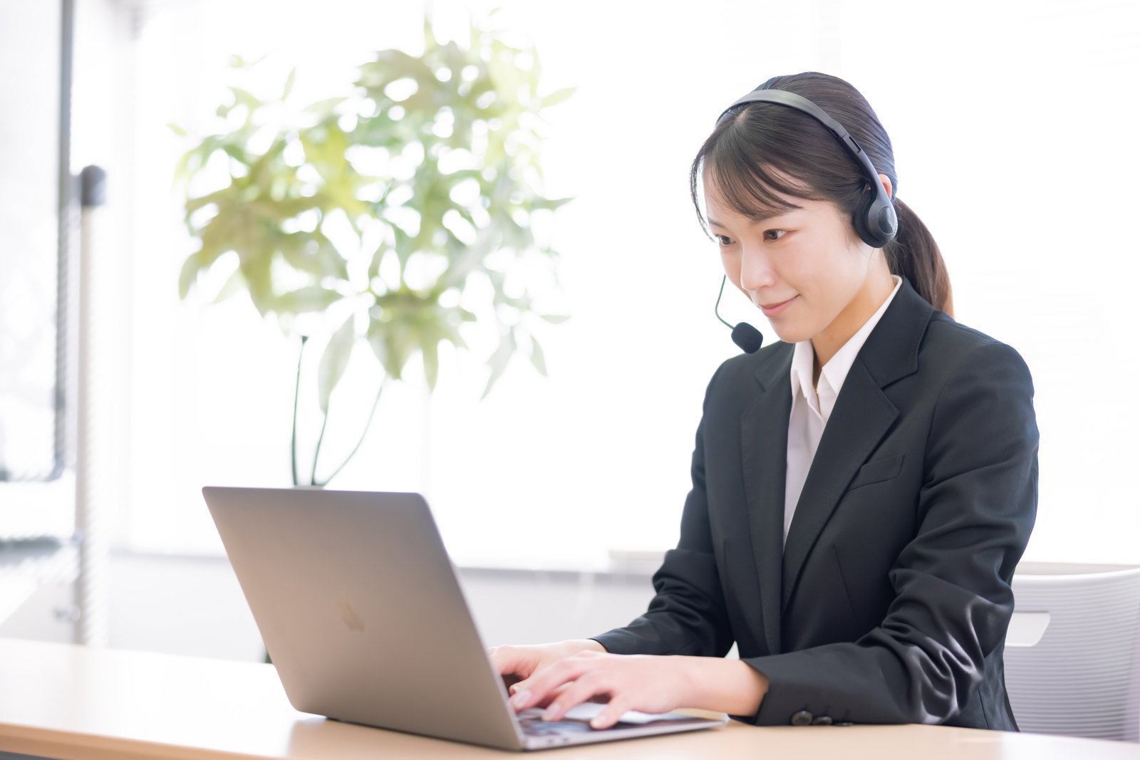 ヘッドセットを着用してパソコンで作業する女性オペレーター［モデル：SAKI］