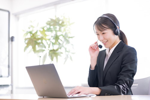 ヘッドセット着用で笑顔でテレアポ業務をこなす女性社員