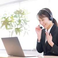 胸に手を当てて対応するコールセンターの女性オペレーターの写真