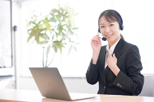 左手を胸に当てて電話対応するコールセンターの女性