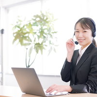 マイクに手を添えるコールセンターの女性オペレーターの写真