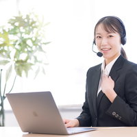 手を胸に当てて笑顔のコールセンターの女性オペレーターの写真