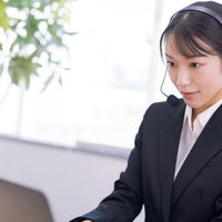 ヘッドセットを着けて真剣な眼差しで業務をこなす女性オペレーターの写真