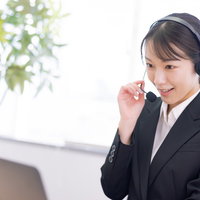 マイクに向かってアナウンスするコールセンターの女性オペレーターの写真