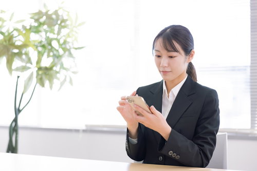 休憩中にスマホを操作する新入社員の女性のビジネスシーン