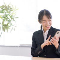スマホを人差し指で操作して笑顔の女性の写真