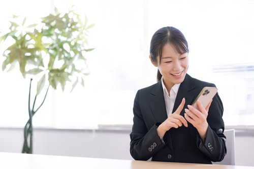 スマホを人差し指で操作して笑顔の女性