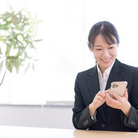 笑顔でスマホを操作する事務員女性のビジネスの写真