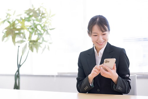 笑顔でスマホを操作する事務員女性のビジネス